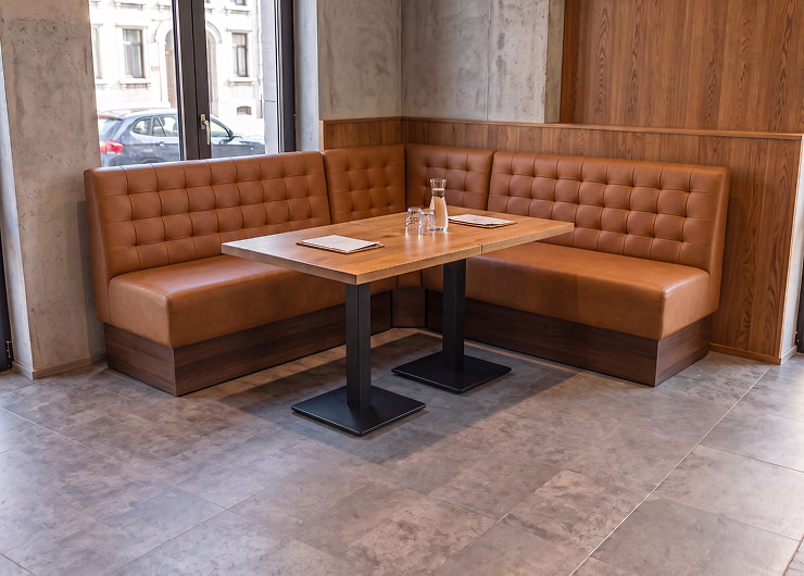 Banquette d’angle en microfibre cognac à haut dossier autour d’une table de restaurant